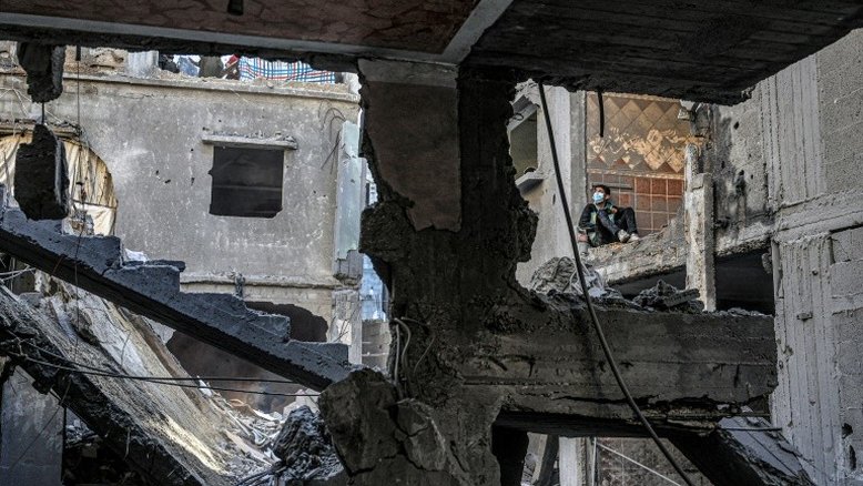 Criança observa edifício destruído por bombardeio israelense em Rafah, sul da Faixa de Gaza