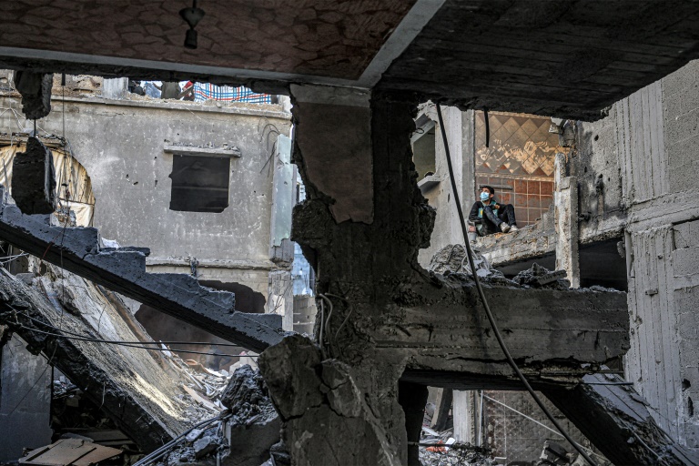 Criança observa edifício destruído por bombardeio israelense em Rafah, sul da Faixa de Gaza