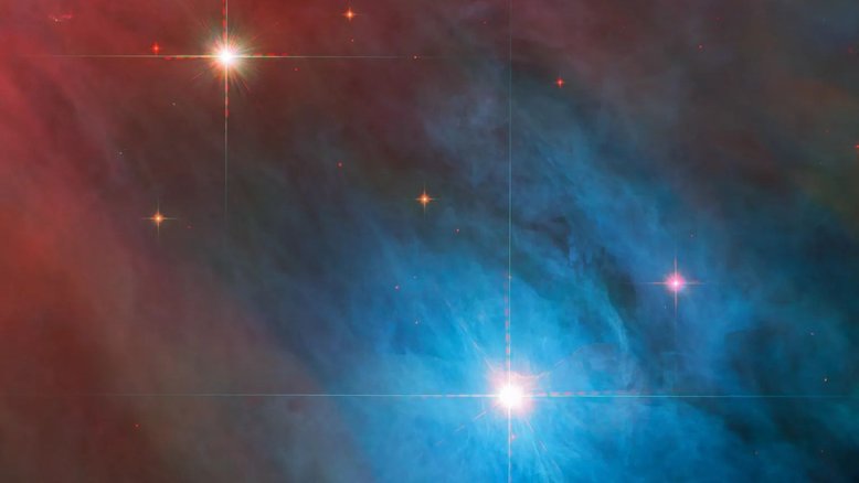A brilhante estrela variável V 372 Orionis domina esta imagem, que também registra uma estrela companheira menor, mais alta e à esquerda. Ambas ficam na Nebulosa de Órion, uma região colossal de formação estelar a cerca de 1,4 mil anos-luz da Terra, na Constelação de Órion. V 372 Orionis é um tipo particular de estrela variável, frequentemente associada a nebulosas difusas, e V 372 Orionis não é exceção: o gás e a poeira, bastante irregulares, permeiam a cena. A imagem sobrepõe dados em comprimentos de onda infravermelhos e também em luz visível