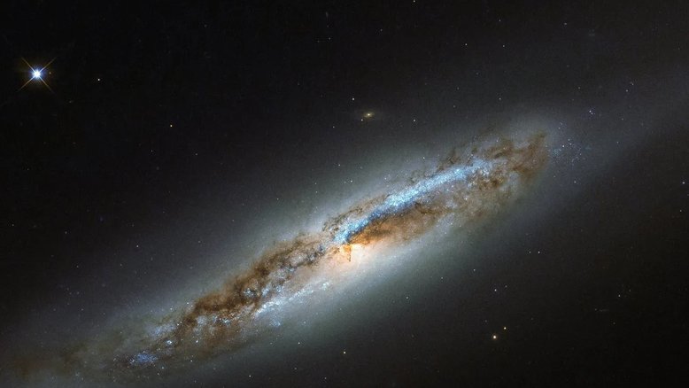 A Constelação de Virgem é especialmente rica em galáxias, em parte devido à presença de uma coleção massiva e ligada gravitacionalmente de mais de 1,3 mil galáxias que formam o Aglomerado de Virgem. Um membro desta comunidade, NGC 4388, aparece nesta imagem. Localizada a cerca de 60 milhões de anos-luz de distância, NGC 4388 está experimentando alguns dos efeitos menos desejáveis ​​que acompanham o fato de pertencer a um aglomerado de galáxias tão massivo. Embora os arredores da galáxia pareçam ser de uma galáxia elíptica, o seu centro exibe notáveis ​​faixas de poeira contidas dentro de dois braços espirais simétricos, que emergem do núcleo brilhante da galáxia, uma das características óbvias de uma galáxia espiral. Apesar de suas características contraditórias, NGC 4388 é classificada como uma galáxia espiral