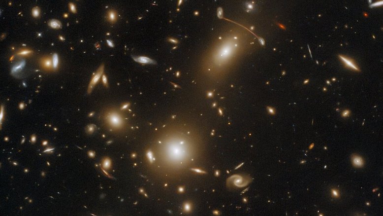 O enorme aglomerado de galáxias Abell 1351 está localizado na Constelação da Ursa Maior, a cerca de 4 bilhões de anos-luz de distância. Nesta imagem, o que se vê como raios de luz são, na verdade, galáxias distantes. As listras são o resultado de lentes gravitacionais, um fenômeno astrofísico que ocorre quando um corpo celeste muito massivo, como um aglomerado de galáxias, distorce o espaço-tempo com força suficiente para afetar o caminho da luz que passa por ele. O fenômeno faz com que a luz pareça passar por uma lente gigantesca