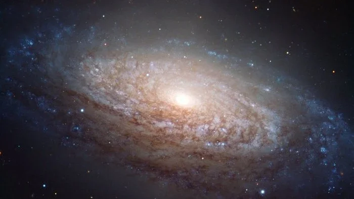 Esta imagem retrata a galáxia NGC 3521 captada pelo Very Large Telescope, no Observatório do Paranal, no Chile. A grande galáxia espiral fica a cerca de 35 milhões de anos-luz de distância, na direção da Constelação de Leão. O registro foi feito a partir de exposições obtidas através de três filtros diferentes que com luz azul, luz amarela/ verde e luz próxima ao infravermelho. Eles são mostrados nesta imagem como azul, verde e vermelho, respectivamente
