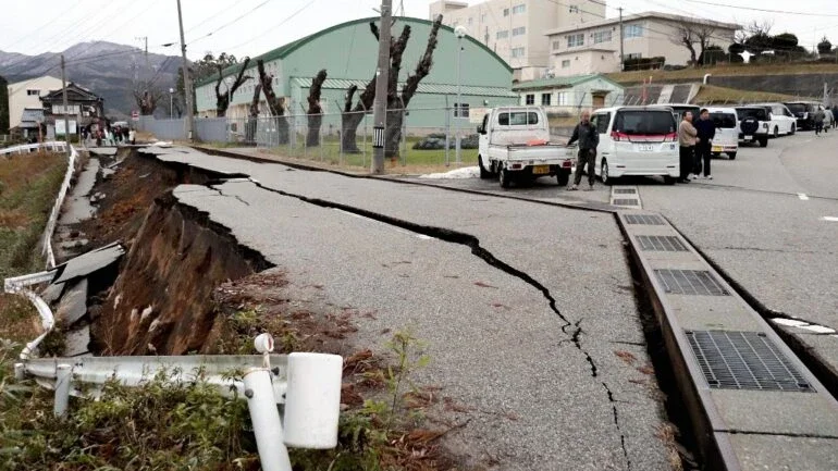 Pessoas ficam próximas a grandes rachaduras na calçada após evacuarem para uma rua na cidade de Wajima, província de Ishikawa