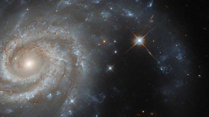 Esta imagem mostra a galáxia espiral IC 438, que fica a cerca de 130 milhões de anos-luz da Terra, na direção da Constelação de Lepus (“A Lebre”). O conjunto estelar de Lepus fica perto da Constelação do Cão Maior, da Constelação do Cão Menor e também da Constelação de Órion. Por isso, muitas representações artísticas trazem a lebre estelar como sendo perseguida por Orion e seus dois cães de caça.  IC 438 é uma galáxia amplamente estudada, pois sediou uma supernova a partir de um sistema binário, ou seja, composto por duas estrelas