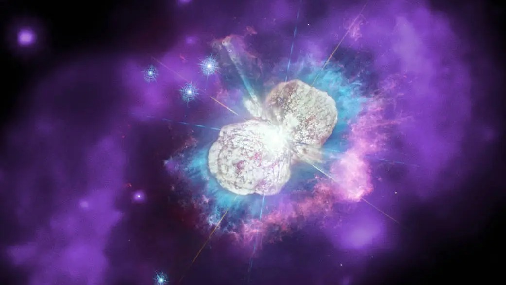 Qual será a próxima estrela da nossa galáxia, a Via Láctea, a explodir em uma supernova? Não há certeza alguma, mas sabe-se que uma forte candidata é Eta Carinae, um sistema volátil que contém duas estrelas massivas que orbitam uma à outra. Esta imagem tem três tipos de luz: dados ópticos (branco), ultravioleta (ciano) e raios X (roxo). As erupções anteriores desta estrela resultaram num anel de gás quente emissor de raios X com cerca de 2,3 anos-luz de diâmetro em torno destas duas estrelas. Eta Carinae está localizada a cerca de 7,5 mil anos luz de distância, na direção da Constelação de Carina (“A Quilha”)