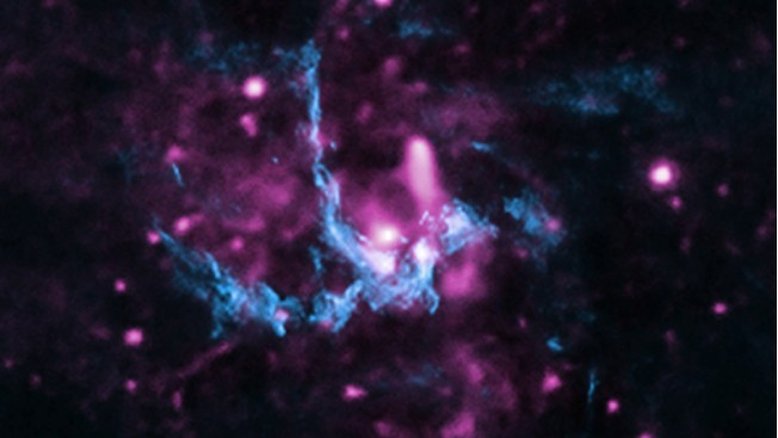 Esta imagem composta apresenta raios X (roxo) e dados de rádio (azul), na região de Sagitário A* (abreviadamente Sgr A*), o buraco negro supermassivo presente no centro da Via Láctea, a nossa galáxia. Nela, vê-se a localização de uma frente de choque, com jatos que se afastam de Sgr A* e viajam pelo espaço até atingir o gás a vários anos-luz de distância. Essa interação também acelera os elétrons, gerando raios X à medida que os elétrons percorrem o caminho do jato, passando pela frente de choque. Sgr A* tem cerca de 4 milhões de vezes a massa do Sol e fica a cerca de 26 mil anos-luz da Terra, na direção da Constelação de Sagitário
