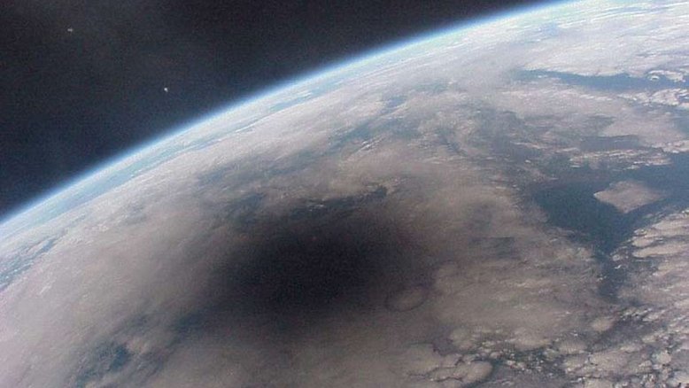 Esta é a aparência da Terra durante um Eclipse Solar. A sombra da Lua pode ser vista escurecendo parte da superfície terrestre. Esta sombra move-se pela Terra a quase 2 mil quilômetros por hora. Apenas os observadores próximos ao centro do círculo escuro veem um Eclipse Solar Total e há quem veja um Eclipse Parcial, dependendo de sua localização, pois conseguem visualizar apenas parte do Sol sendo bloqueado pela Lua. Esta imagem retrata o Eclipse Solar de 11 de agosto de 1999. Os dois pequenos pontos brilhantes, que aparecem no canto superior esquerdo, são Júpiter e Saturno