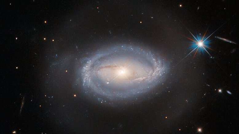 Localizada a 390 milhões de anos-luz da Terra, na Constelação da Lira, Z 229-15 é um objeto celeste com várias definições: um núcleo galáctico ativo (AGN), um quasar ou uma galáxia Seyfert. O fato é que Z 229-15 reúne tudo isso ao mesmo tempo. Um AGN é uma pequena região, no coração de certas galáxias, cuja luminosidade extra se dá pela presença de um buraco negro supermassivo que libera uma grande quantidade de energia em todo o espectro eletromagnético. Os quasares são um tipo particular de AGN, tão brilhantes que impedem a observação do resto da galáxia. Nas galáxias Seyfert, apesar de hospedarem quasares, a observação do entorno ainda é possível. Portanto, Z 229-15 é uma galáxia Seyfert, que contém um quasar e que, por definição, hospeda um AGN
