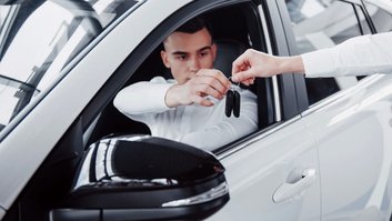 dois-homens-estao-no-showroom-contra-carros-close-up-de-um-gerente-de-vendas-em-um-terno-que-vende-um-carro-para-um-cliente-o-vendedor-entrega-a-chave-ao-cliente-1
