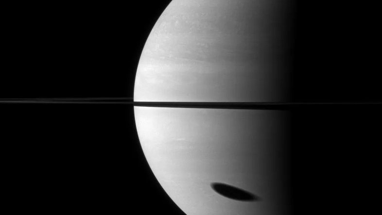 Com o Eclipse Solar Total acontecendo nesta segunda-feira, dia 8, é possível se perguntar: os eclipses acontecem em outros planetas? Sim e certamente o fazem no sistema de Saturno, com resultados espetaculares. Saturno tem diversas luas, sem falar nos anéis, o que faz com que os eclipses aconteçam com relativa frequência durante certas estações. Nesta imagem, por exemplo, a sua lua Titã lança uma sombra no topo das nuvens do planeta. Um observador localizado dentro do círculo escuro veria um eclipse solar. Os anéis, vistos quase de lado, estão no equador de Saturno