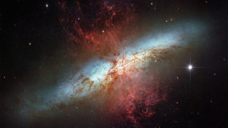 Localizada a 12 milhões de anos-luz de distância, na direção da Constelação da Ursa Maior, M82 é também chamada de “Galáxia do Charuto”, devido à forma elíptica alongada, em função da inclinação do seu disco estrelado em relação ao nosso ângulo de visão. M82 é uma magnífica galáxia estelar, pois em toda a sua região central, estrelas jovens estão nascendo dez vezes mais rápido do que na nossa galáxia, a Via Láctea. Estas numerosas novas estrelas quentes não só emitem radiação, mas também partículas carregadas que formam o chamado vento estelar