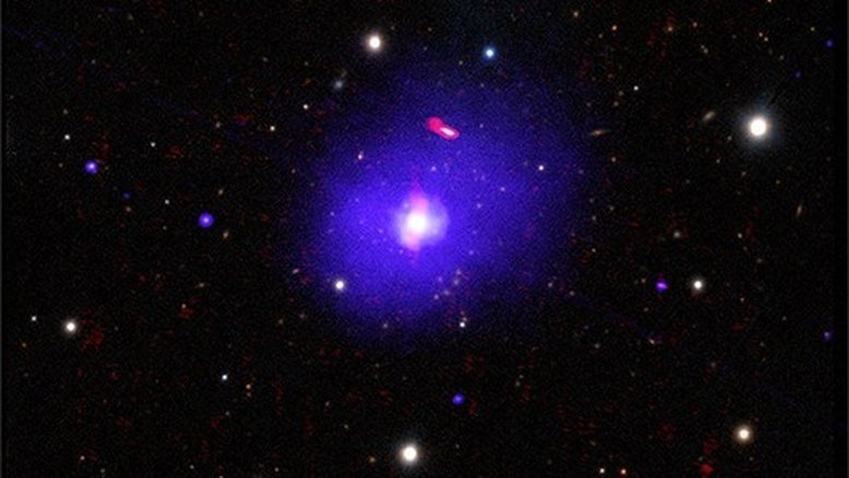 H1821+643 é um quasar alimentado por um buraco negro supermassivo, localizado a cerca de 3,4 bilhões de anos-luz da Terra, na direção da Constelação de Draco (“O Dragão”). A partir de suas observações, foi possível determinar a rotação de seu buraco negro, que tem entre três e 30 bilhões de massas solares, o que o torna um dos mais massivos conhecidos. A título de comparação, o buraco negro supermassivo no centro da Via Láctea tem cerca de quatro milhões de massas solares. Esta imagem composta de H1821+643 combina dados de raios X (azul), rádio (vermelho) e luz óptica (branco e amarelo)
