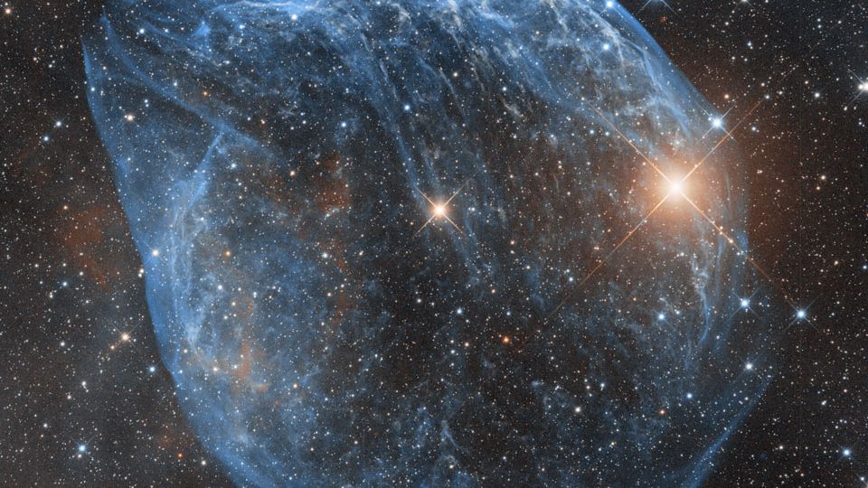 Soprada por ventos rápidos de uma estrela quente e massiva, esta bolha cósmica é muito maior do que parece ser. Catalogada como Sharpless 2-308, ela fica a cerca de 5,2 mil anos-luz de distância, na direção da Constelação do Cão Maior. A estrela massiva que criou a bolha, do tipo Wolf-Rayet, é o ponto mais brilhante perto do centro da nebulosa. As estrelas Wolf-Rayet têm mais de 20 vezes a massa do Sol e acredita-se que estejam em uma breve fase pré-supernova. A nebulosa soprada pelos ventos estelares tem uma idade de cerca de 70 mil anos
