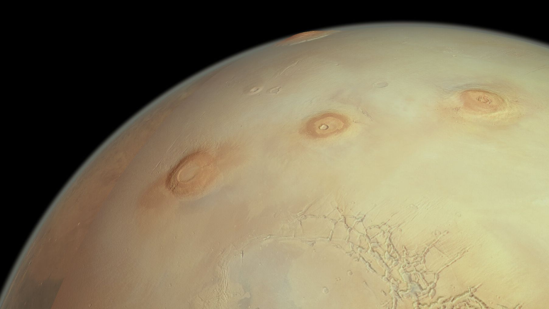 Esta perspectiva oblíqua da superfície de Marte celebra o marco da órbita de número 25 mil realizada pela missão Mars Express, da ESA, em torno do planeta vermelho. A escala vertical está exagerada por um fator de aproximadamente três, fazendo com que os vulcões pareçam ser proporcionalmente três vezes mais altos do que realmente são. Três dos famosos vulcões colossais de Marte aparecem, da esquerda para a direita: Arsia Mons, Pavonis Mons e Ascraeus Mons. O monte do maior vulcão de Marte, Olympus Mons, aparece no topo da imagem, enquanto o terreno irregular do Noctis Labyrinthus está em primeiro plano