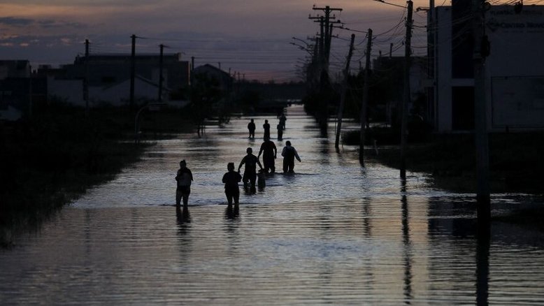 Pessoas caminham por uma rua inundada de Eldorado do Sul, Rio Grande do Sul, Brasil