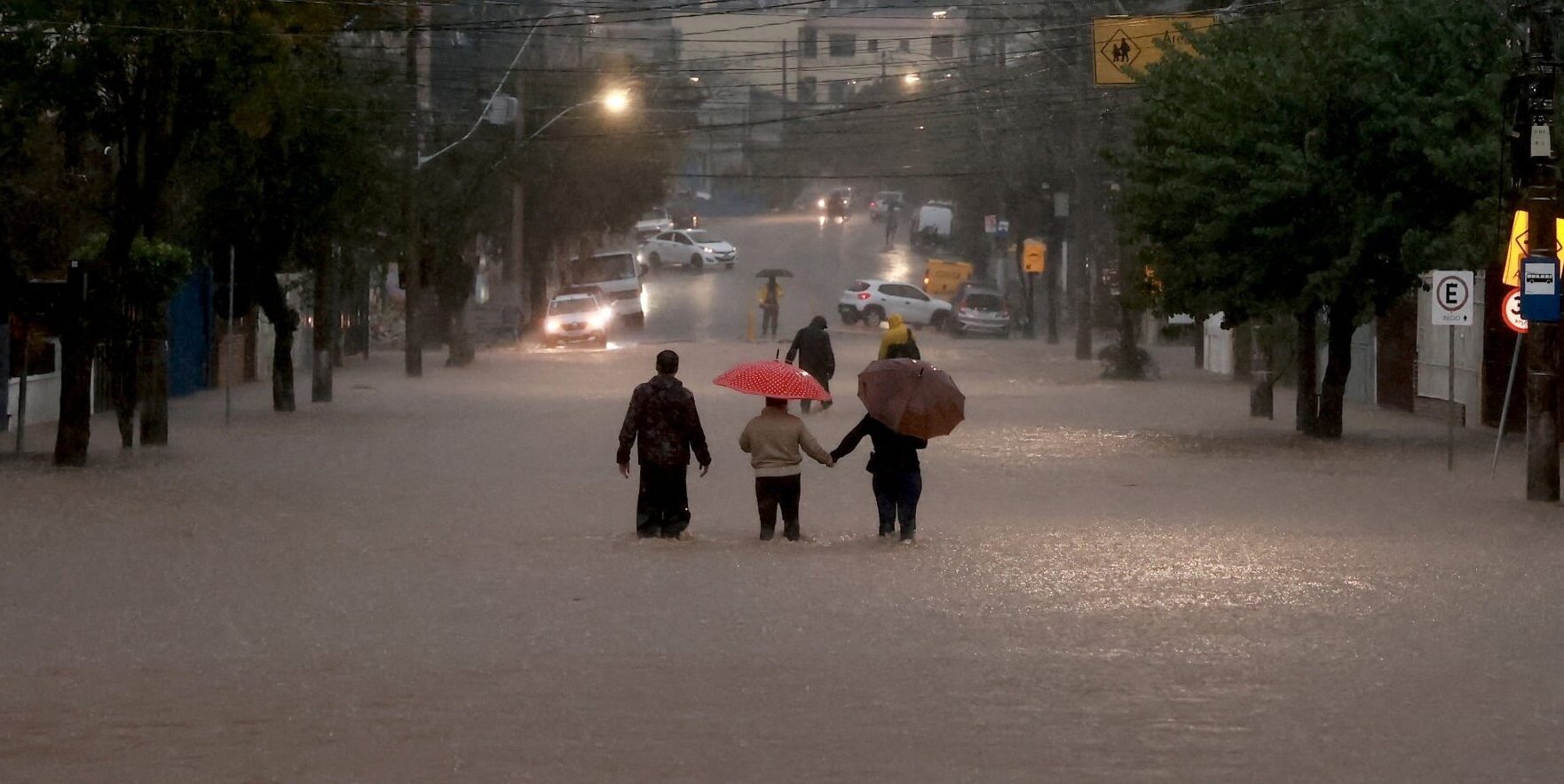 Pessoas caminham de guarda-chuva em rua inundada de Porto Alegre (RS)