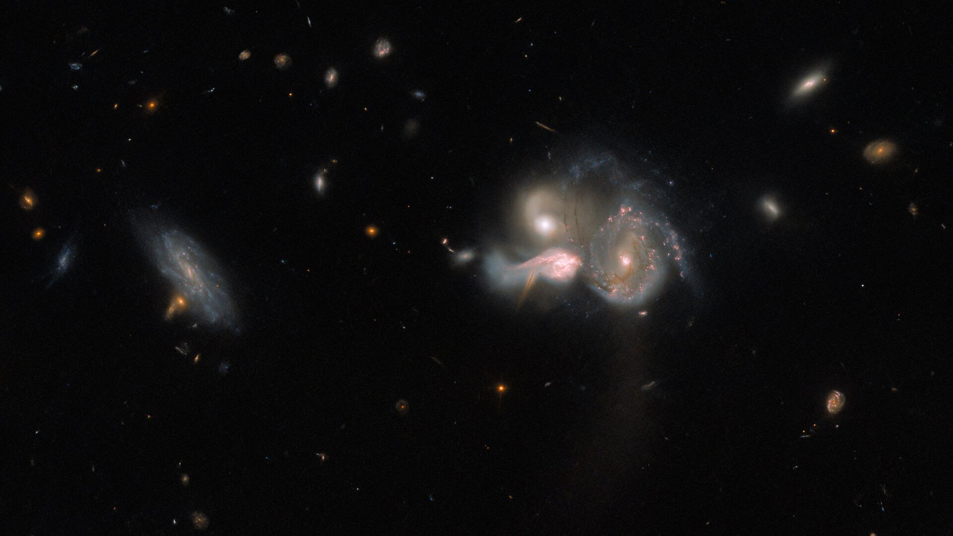 Este espetacular trio de galáxias em fusão está localizado a cerca de 1,04 bilhões de anos luz, na Constelação de Boötes (“O Boieiro”). Em rota de colisão, as três galáxias acabarão por se fundir em uma única galáxia maior, distorcendo suas estruturas espirais por conta da interação gravitacional. À esquerda, também vê-se uma quarta galáxia que parece flutuar serenamente ao lado da colisão. O trio à direita, conhecido como SDSSCGB 10189, é uma combinação relativamente rara de grandes galáxias com formação estelar, distantes apenas 50 mil anos-luz uma da outra