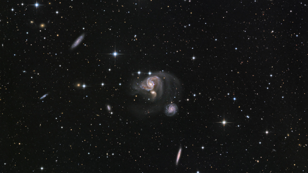 Esta imagem telescópica nítida revela o grupo de galáxias HCG 91 com muitos detalhes. As três galáxias espirais coloridas, no centro do campo de visão, estão presas num cabo de guerra gravitacional, e as suas interações produzem caudas de maré, fracas mas visíveis, com mais de 100 mil anos-luz de comprimento. Seus encontros desencadeiam uma furiosa formação de estrelas. HCG 91 fica a cerca de 320 milhões de anos-luz de distância, na Constelação de Piscis Austrinus (“O Peixe do Sul”)