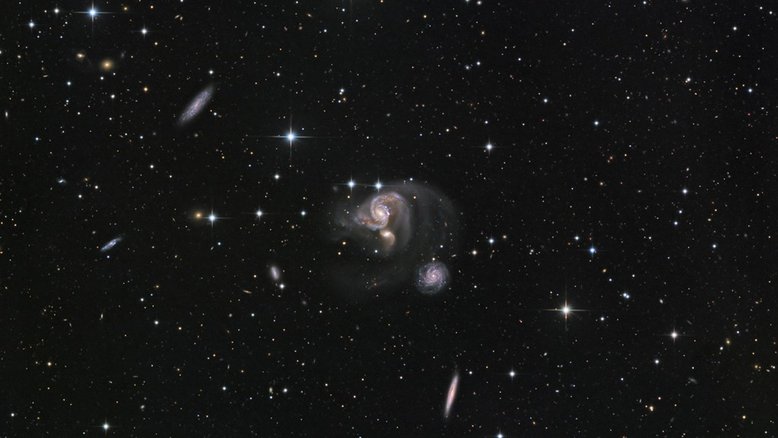 Esta imagem telescópica nítida revela o grupo de galáxias HCG 91 com muitos detalhes. As três galáxias espirais coloridas, no centro do campo de visão, estão presas num cabo de guerra gravitacional, e as suas interações produzem caudas de maré, fracas mas visíveis, com mais de 100 mil anos-luz de comprimento. Seus encontros desencadeiam uma furiosa formação de estrelas. HCG 91 fica a cerca de 320 milhões de anos-luz de distância, na Constelação de Piscis Austrinus (“O Peixe do Sul”)
