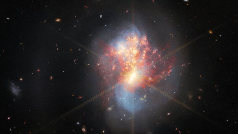 Esta imagem, feita pelo Telescópio Espacial James Webb, mostra IC 1623, um par entrelaçado de galáxias em interação, a cerca de 270 milhões de anos-luz da Terra, na Constelação de Cetus. As duas galáxias estão mergulhando de cabeça uma na outra, em um processo de fusão. A sua colisão desencadeou uma onda frenética de formação estelar, a uma taxa mais de vinte vezes superior à da Via Láctea, a nossa galáxia. Esta interação é particularmente brilhante em comprimentos de onda infravermelhos. O núcleo luminoso da fusão revela-se muito cintilante e altamente compacto, a ponto de os picos de difração do Webb aparecerem no topo
