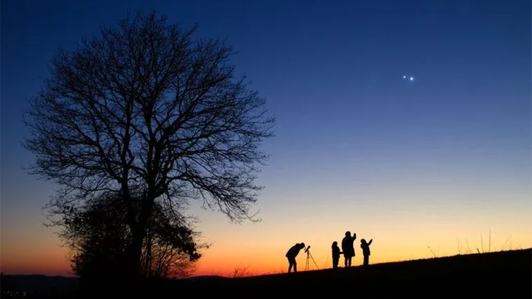 Assim como em março do ano passado, período no qual foi registrada esta imagem, os dois planetas mais brilhantes do céu noturno, Júpiter e Vênus, estão atualmente próximos no céu. Este ano, ambos estão aparecendo ao Leste, praticamente ao amanhecer. Em 2023, o espetáculo ocorreu logo após o pôr do Sol, como nesta foto, feita em Wiltingen, na Alemanha, que mostra o astrofotógrafo, sua esposa e seus dois filhos. É claro que Vênus fica muito mais próximo ao Sol e à Terra do que Júpiter: a aparente proximidade entre os planetas no céu é apenas angular, em função da posição de cada um em suas órbitas