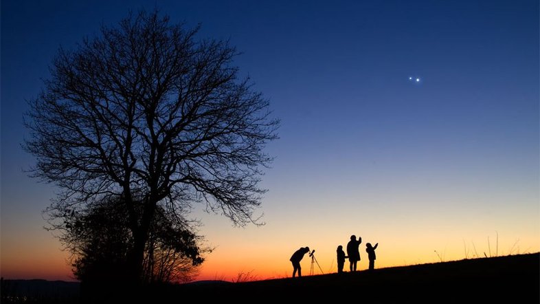 Assim como em março do ano passado, período no qual foi registrada esta imagem, os dois planetas mais brilhantes do céu noturno, Júpiter e Vênus, estão atualmente próximos no céu. Este ano, ambos estão aparecendo ao Leste, praticamente ao amanhecer. Em 2023, o espetáculo ocorreu logo após o pôr do Sol, como nesta foto, feita em Wiltingen, na Alemanha, que mostra o astrofotógrafo, sua esposa e seus dois filhos. É claro que Vênus fica muito mais próximo ao Sol e à Terra do que Júpiter: a aparente proximidade entre os planetas no céu é apenas angular, em função da posição de cada um em suas órbitas