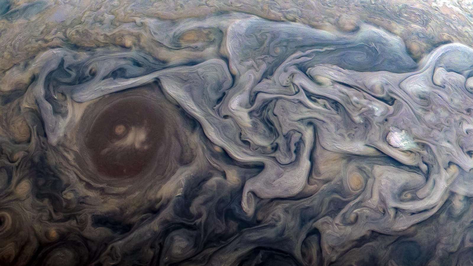 Características atmosféricas dramáticas, no Hemisfério Norte de Júpiter, são o destaque desta imagem feita pela sonda Juno, da NASA. A nova perspectiva mostra nuvens rodopiantes, que circundam uma estrutura circular, dentro de uma região de corrente de jato chamada “Jet N6”. Feito em fevereiro de 2019, o registro aconteceu enquanto a espaçonave realizava seu 18º sobrevôo próximo ao planeta gigante gasoso. Juno estava a cerca de 13 mil km do topo das nuvens do planeta, acima de uma latitude de aproximadamente 55 graus ao Norte