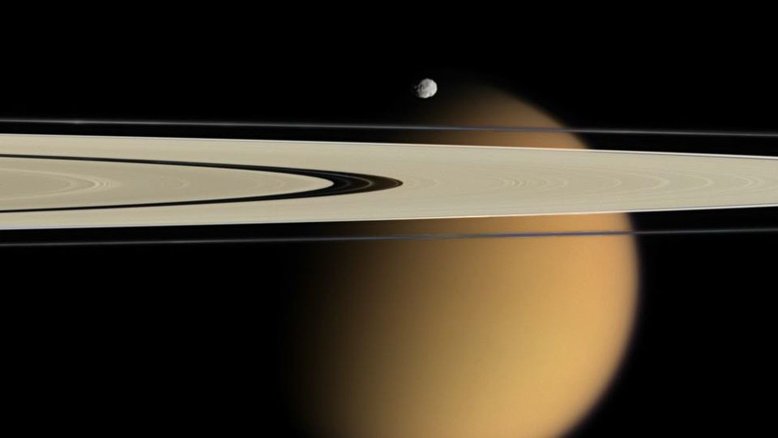 Ao orbitar Saturno, é possível observar sobreposições entre luas e anéis de tirar o fôlego. Uma dessas vistas privilegiadas foi registrada pela missão Cassini. Em abril de 2006, a espaçonave capturou os anéis A e F de Saturno estendendo-se em frente à lua Titã envolta em nuvens. Perto dos anéis e aparecendo logo acima de Titã estava Epimeteu, uma outra lua do planeta, mas que orbita fora do anel F. O espaço escuro no anel A é chamado de Lacuna Encke, embora a pequena lua Pã orbite nesse espaço