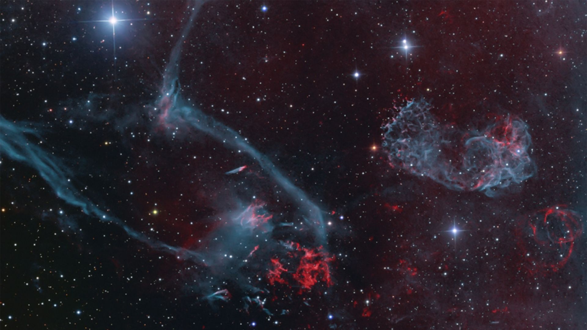 Resultado da explosão de uma estrela massiva, o remanescente de supernova Puppis A está a cerca de 7 mil anos-luz de distância, na direção da Constelação de Puppis (“A Popa”). À medida que o remanescente da supernova (no canto superior direito) se expande em seu ambiente aglomerado e não uniforme, filamentos de átomos de oxigênio em choque brilham em tons verde-azulados. Hidrogênio e nitrogênio estão em vermelho. A luz da própria supernova inicial, desencadeada pelo colapso do núcleo da estrela massiva, teria chegado à Terra há cerca de 3,7 mil anos. Ainda brilhando em todo o espectro eletromagnético, Puppis A continua sendo uma das fontes mais cintilantes de raios-X no céu