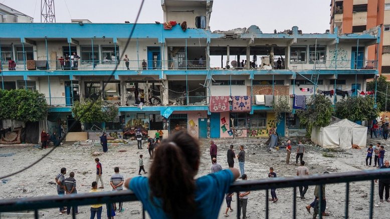 Uma menina palestina observa escola da ONU que foi atingida durante o bombardeio israelense em Gaza