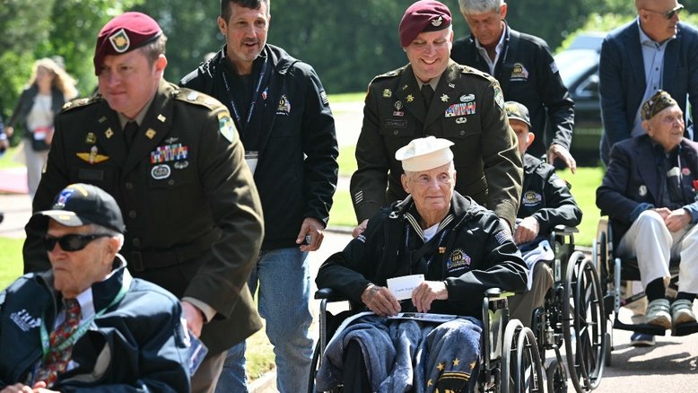 Militares dos EUA escoltam veteranos da Segunda Guerra Mundial em cadeiras de rodas durante cerimônia que marca o 80º aniversário do "Dia D"