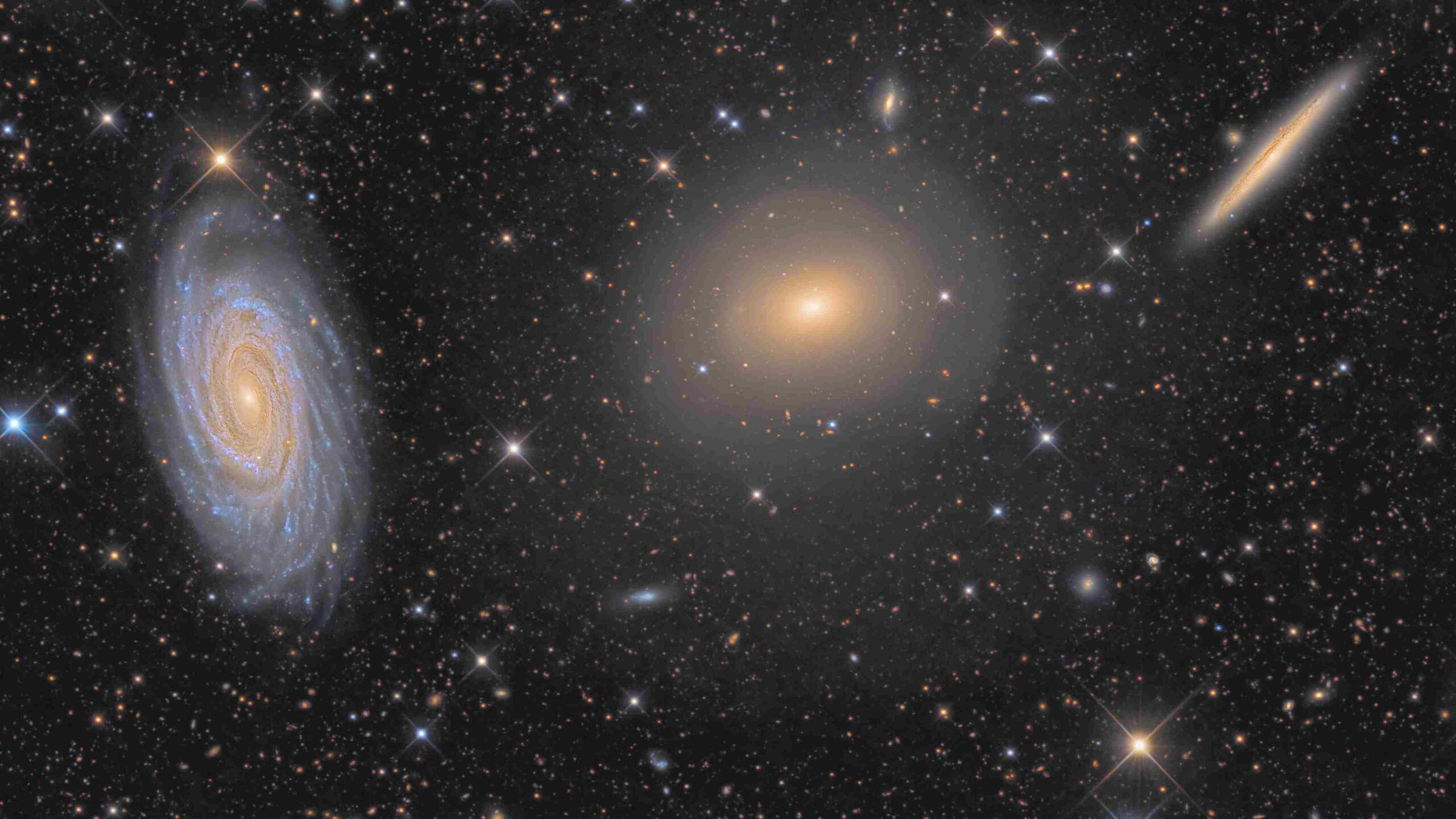 Este trio de galáxias está localizado na boreal Constelação de Draco (“O Dragão”). Da esquerda para a direita, estão a espiral NGC 5985, a galáxia elíptica NGC 5982 e a espiral NGC 5981. Embora seja demasiado pequeno para ser um aglomerado e não tenha sido catalogado como um grupo compacto, as três galáxias ficam a cerca de 100 milhões de anos-luz do planeta Terra. O núcleo brilhante da impressionante espiral NGC 5985 mostra emissões proeminentes em comprimentos de onda específicos de luz, o que a torna uma Seyfert, um tipo de galáxia com núcleo ativo. Este registro também sugere um halo tênue e escuro, junto com conchas de bordas afiadas que cercam a elíptica NGC 5982, uma evidência de fusões galácticas passadas