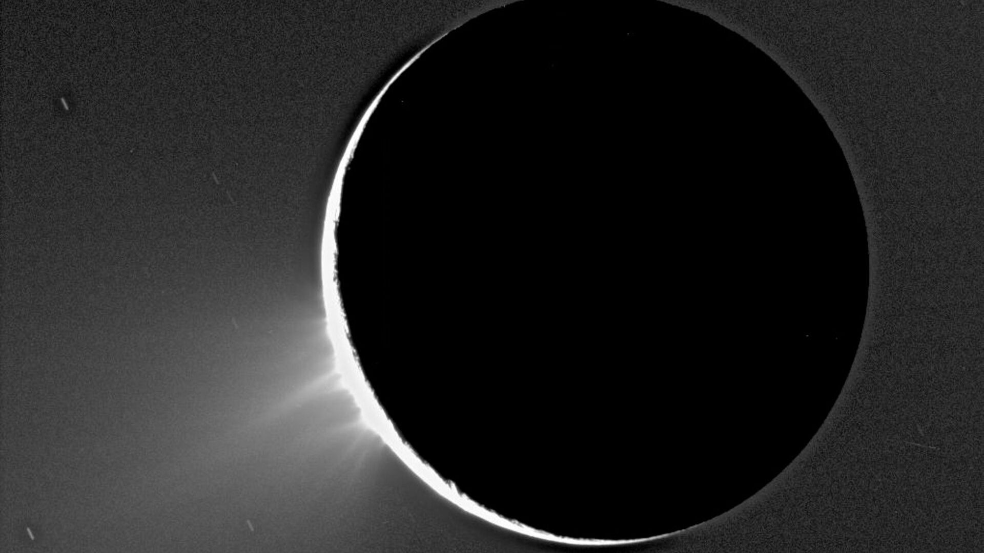 Jatos de partículas geladas são expelidos de Encélado, uma das luas de Saturno, nesta imagem registrada pela missão Cassini, em novembro de 2005. Esta e outras imagens de Encélado iluminado pelo Sol mostram sprays, em forma de fonte, de um material fino que se eleva sobre a região polar Sul. Esta imagem foi feita em um ângulo mais ou menos de lado para as fraturas apelidadas de “listras de tigres”, observadas em imagens anteriores na superfície de Encélado. Foram observadas plumas discretas, de uma variedade de tamanhos, acima da sua borda
