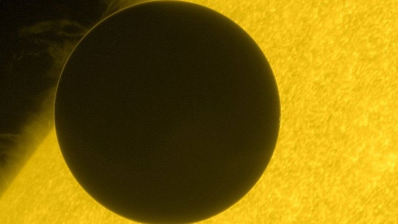 Neste trânsito, que ocorreu em junho de 2012, Vênus cruzou a borda do Sol e foi registrado nesta imagem deslumbrante da espaçonave Hinode. O tempo de cruzamento durante esses trânsitos raros foi usado historicamente como parâmetro para medir a distância de Vênus e, com isso, determinar um valor para a distância entre a Terra e o Sol, uma referência de medida que recebe o nome de unidade astronômica. Com a avanço da tecnologia, esse tipo de observação também serve para revelar a turbulenta superfície solar, com proeminências elevadas acima da borda do Sol por campos magnéticos tortuosos. O fino anel brilhante, em torno da silhueta escura do planeta, é a luz solar refratada pela espessa atmosfera de Vênus