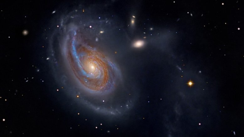 A peculiar galáxia espiral Arp 78 fica dentro dos limites da Constelação de Áries. A cerca de 100 milhões de anos-luz, ela tem aproximadamente 200 mil anos-luz de diâmetro. Também conhecida como NGC 772, ela ostenta um braço espiral externo proeminente, que é impulsionado por marés gravitacionais. As interações com a sua galáxia companheira NGC 770, vista acima e à direita da espiral maior, são provavelmente as responsáveis. A aparência difusa e elíptica de NGC 770 contrasta com as estrelas pontiagudas da Via Láctea, que aparecem em primeiro plano na imagem