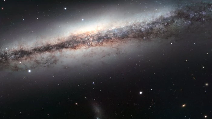 NGC 3628 é uma galáxia espiral que pertence ao famoso grupo de galáxias batizado de Leo Triplet, o Trio de Leão, localizado a cerca de 35 milhões de anos-luz de distância, na direção da Constelação de Leão. Os outros membros ilustres dessa família são duas galáxias espirais conhecidas como Messier 65 e Messier 66. NGC 3628, que está retratada nesta imagem, é a mais fraca do trio e esconde a sua estrutura espiral porque é vista de lado. Sua característica mais marcante é uma faixa escura de poeira que atravessa o plano do disco, distorcida para fora, como consequência da interação gravitacional com suas  companheiras