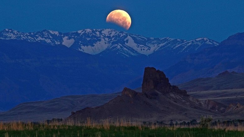 Uma Lua Cheia bastante rara domina esta imagem, registrada em junho de 2012. Pouco antes de ficar totalmente iluminada e se pôr, atrás da Cordilheira Absaroka - perto de Cody, em Wyoming, nos EUA -, a sombra da Terra se fez notar em nosso satélite natural. Este Eclipse Lunar Parcial foi visível na maior parte da América do Norte, América do Sul e todo o Leste da Ásia. Os eclipses lunares ocorrem cerca de duas vezes por ano