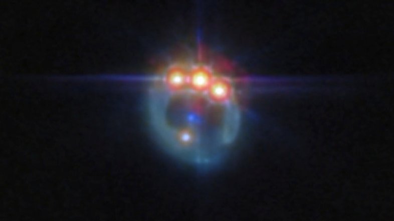 Esta imagem, feita pelo Telescópio Espacial James Webb, apresenta a lente gravitacional do quasar conhecido como RX J1131-1231, localizado a cerca de 6 bilhões de anos-luz da Terra, na Constelação de Crater. Nele, a galáxia em primeiro plano mancha a imagem do quasar de fundo, em um arco brilhante, e cria quatro imagens do objeto. As lentes gravitacionais, conforme descreve a teoria da relatividade, de Albert Einstein, agem como telescópios naturais, pois ampliam a luz. O fenômeno reflete o fato de que toda a matéria no Universo distorce o espaço ao seu redor. Assim, em volta de objetos muito massivos, a luz parece se curvar de seu caminho original