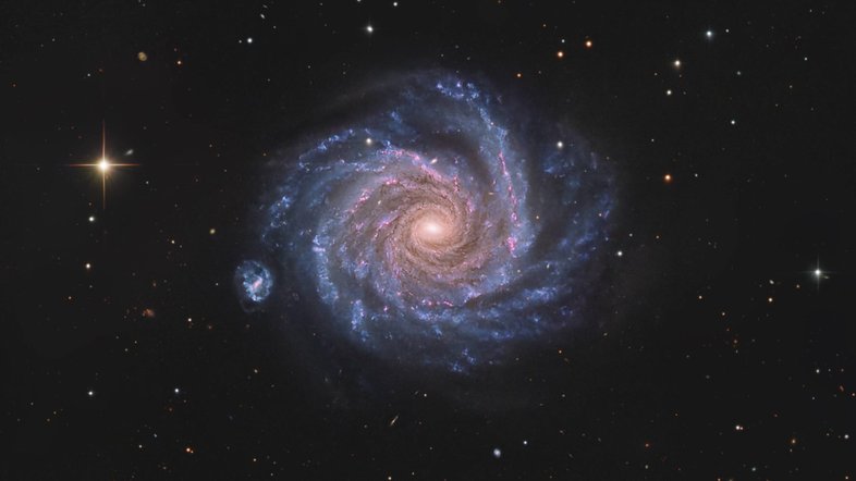 A partir da Via Láctea, vê-se a galáxia NGC 1232 de frente. Com quase 200 mil anos-luz de diâmetro, esta galáxia espiral está localizada a cerca de 47 milhões de anos-luz de distância, na Constelação de Eridanus. Nesta imagem, vê-se sua mudança de cores: da luz amarelada das estrelas velhas, no centro, para jovens aglomerados de estrelas azuis e regiões avermelhadas de formação estelar, ao longo dos braços espirais. A pequena galáxia companheira, à esquerda, é a espiral barrada NGC 1232A. A estrela brilhante, com aparência pontiaguda, está muito mais próxima do que NGC 1232, pois fica dentro da Via Láctea
