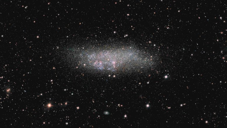 Nomeada em homenagem aos três astrônomos que contribuíram para sua descoberta e identificação, Wolf - Lundmark - Melotte (WLM) é uma galáxia anã solitária. Localizada na direção da Constelação de Cetus, a cerca de 3 milhões de anos-luz da Via Láctea, ela é um dos membros do nosso grupo de galáxias local. Regiões de formação de estrelas rosadas e estrelas quentes, jovens e azuladas, são notáveis. Estrelas mais velhas e frias, amareladas, desaparecem no halo da pequena galáxia, que se estende por cerca de 8 mil anos-luz