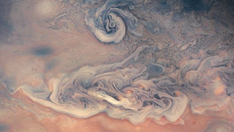 O que cria as cores nas nuvens de Júpiter? Ninguém sabe ao certo. A espessa atmosfera do planeta é composta principalmente de hidrogênio e hélio, elementos que são incolores nas baixas temperaturas do topo das nuvens jovianas. Por isso, a origem das cores continua sendo um tópico de pesquisa, embora pequenas quantidades de hidrossulfeto de amônio sejam um dos principais candidatos. Esta imagem, feita pela sonda robótica Juno, revela que as nuvens mais claras estão normalmente mais altas do que as mais escuras. As nuvens claras giram em torno de regiões avermelhadas, no canto inferior direito, enquanto parecem cobrir alguns domínios mais escuros, no canto superior direito