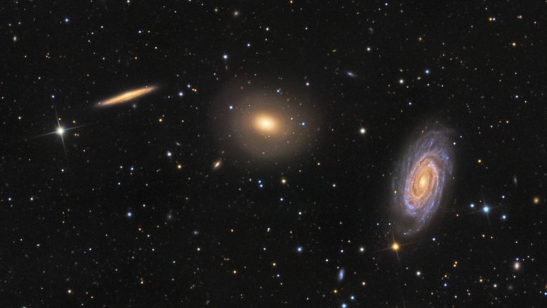 Este intrigante trio de galáxias está localizado na Constelação de Draco (“O Dragão”). Da esquerda para a direita estão a espiral vista de lado NGC 5981, a galáxia elíptica NGC 5982 e a espiral vista de frente NGC 5985. Todas estão a cerca de 100 milhões de anos-luz do planeta Terra. O núcleo brilhante da espiral frontal NGC 5985 mostra emissões proeminentes em comprimentos de onda específicos de luz, o que a torna uma Seyfert, um tipo de galáxia ativa. Esta exposição profunda também sugere conchas tênues em torno da elíptica NGC 5982, o que evidencia fusões galácticas no passado