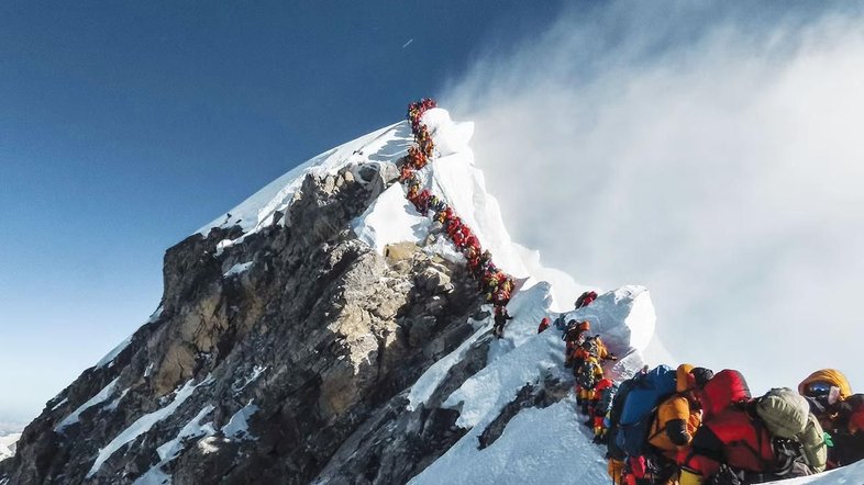 Pessoas em fila escalam montanha gelada