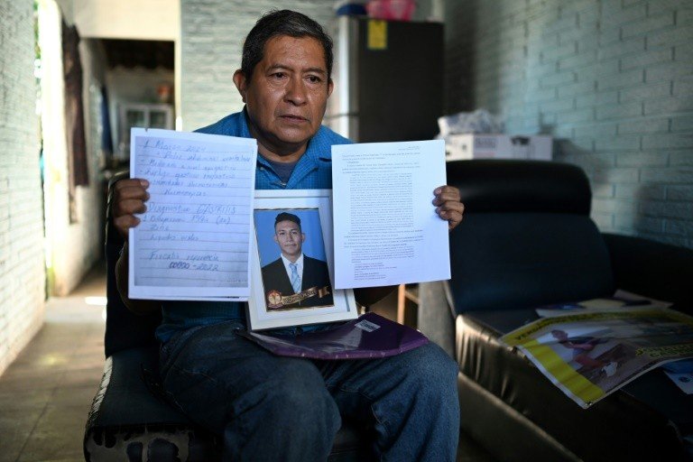 Bukele na CPI do Crime Organizado? Entenda como isso pode acontecer 2 Reynaldo Santos mostra em sua casa em Soyapango, no dia 25 de outubro de 2024, documentos e uma foto de seu filho Jonathan, preso no estado de exceção imposto em El Salvador para combater gangues - AFP