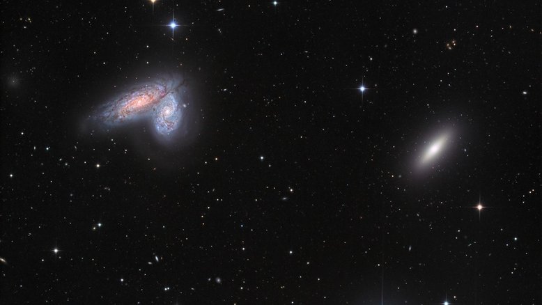 O par de galáxias espirais NGC 4567 e NGC 4568 compartilham esta imagem com a solitária galáxia elíptica NGC 4564. Todos são membros do aglomerado de galáxias de Virgem, localizado na Constelação de Virgem. Com seus braços espirais clássicos, faixas de poeira e aglomerados de estrelas, as galáxias gêmeas espirais estão bem próximas e, por isso, não parecem muito distorcidas pelas marés gravitacionais. Contudo, sabe-se que suas nuvens moleculares estão colidindo e formando aglomerados estelares massivos. NGC 4567 e NGC 4568 estão a cerca de 52 milhões de anos-luz de distância da Terra