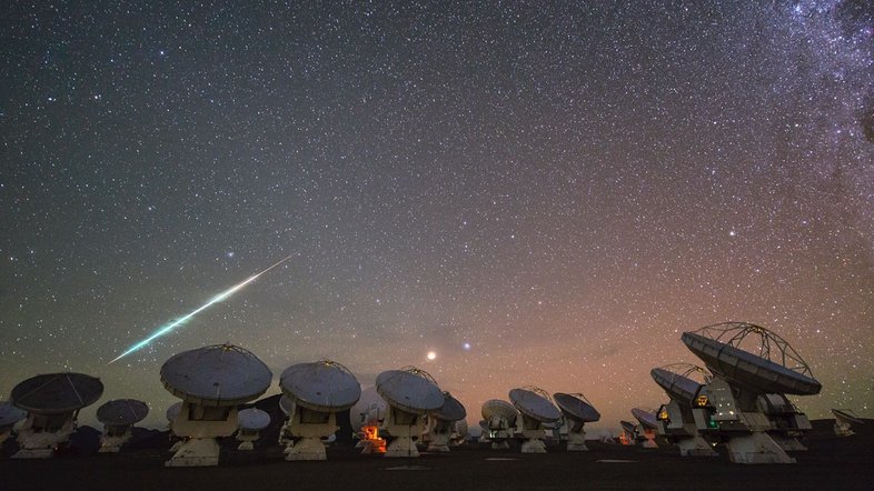 Esta imagem mostra o observatório do Atacama Large Millimeter/submillimeter Array (ALMA). Localizado a 5 mil metros acima do nível do mar, no planalto do Chajnantor, nos Andes chilenos, ele tem 66 antenas de alta precisão para estudar o espaço interestelar. O dardo de luz sobre a rede do ALMA é um meteoro que queima ao entrar na atmosfera da Terra. A estrela Alfa e mais brilhante da Constelação de Virgem, a azulada Spica, e o avermelhado planeta Marte brilham intensamente no centro da imagem