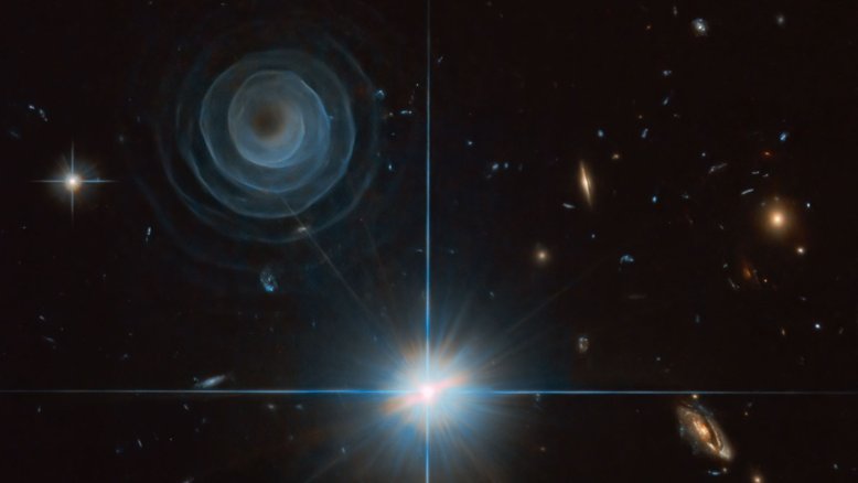 O que criou a estranha estrutura em espiral no canto superior esquerdo? Ninguém tem certeza, embora o fenômeno esteja provavelmente relacionado com uma estrela, em um sistema estelar binário, que entrou em fase de nebulosa planetária, quando a sua atmosfera exterior é ejetada. O sistema estelar que o criou é conhecido como LL Pegasi (ou também AFGL 3068 e IRAS 23166+1655). A razão pela qual a espiral brilha é também um mistério, sendo que uma das principais hipóteses é a de que seria resultado da luz refletida de estrelas próximas. LL Pegasi está a cerca de 135 anos-luz de distância, na direção da Constelação do Pégaso