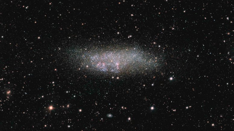 Fazendo homenagem aos três astrônomos que contribuíram para sua descoberta, a galáxia anã Wolf - Lundmark - Melotte (WLM) é solitária. Localizada na Constelação de Cetus, a cerca de 3 milhões de anos-luz da Via Láctea, ela é um dos membros mais remotos do nosso grupo local de galáxias. Nela, regiões de formação de estrelas rosadas e azuladas contrastam com estrelas mais velhas, frias e amareladas. Este retrato nítido de WLM foi capturado pelo Observatório do Paranal, no Chile