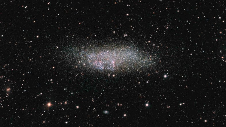 Fazendo homenagem aos três astrônomos que contribuíram para sua descoberta, a galáxia anã Wolf - Lundmark - Melotte (WLM) é solitária. Localizada na Constelação de Cetus, a cerca de 3 milhões de anos-luz da Via Láctea, ela é um dos membros mais remotos do nosso grupo local de galáxias. Nela, regiões de formação de estrelas rosadas e azuladas contrastam com estrelas mais velhas, frias e amareladas. Este retrato nítido de WLM foi capturado pelo Observatório do Paranal, no Chile