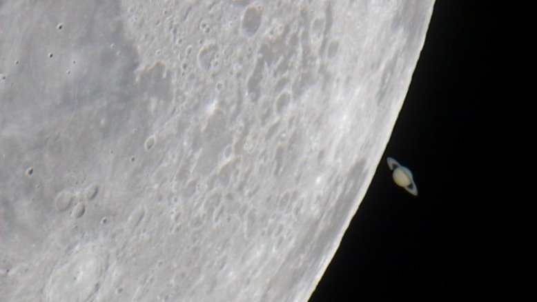 Em maio de 2007, poucos dias depois de partilhar o céu noturno ocidental com Vênus, a Lua passou por Saturno, ocultando temporariamente o planeta conhecido por seus anéis. Como a Lua e os planetas vagam pelo céu perto do plano da eclíptica, tais eventos de ocultação não são incomuns, embora sejam dramáticos em imagens telescópicas. Neste registro, feito no Observatório Weikersheim, no Sul da Alemanha, Saturno aparece emergindo de trás da Lua, dando a ilusão de que está próximo de sua borda. No entanto, a Lua está a apenas 400 mil quilômetros de distância, enquanto Saturno fica a 1,4 bilhões de quilômetros da Terra